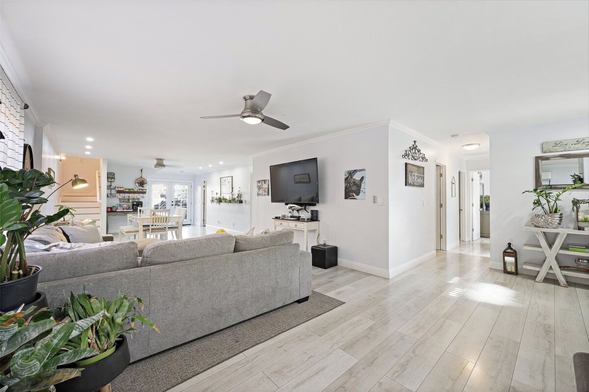 Ein modernes Wohnzimmer mit grauem Sofa, Flachbildfernseher und Deckenventilator.