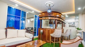Een woonkamer met een bank, stoelen, een houten salontafel en een bar met krukken.