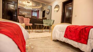 A hotel room with two beds, a large mirror, a chandelier, and a seating area with chairs.