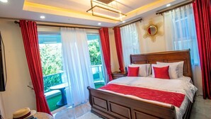 Een slaapkamer met een houten bed, rood-witte gordijnen, een plafondlamp en uitzicht op groen.