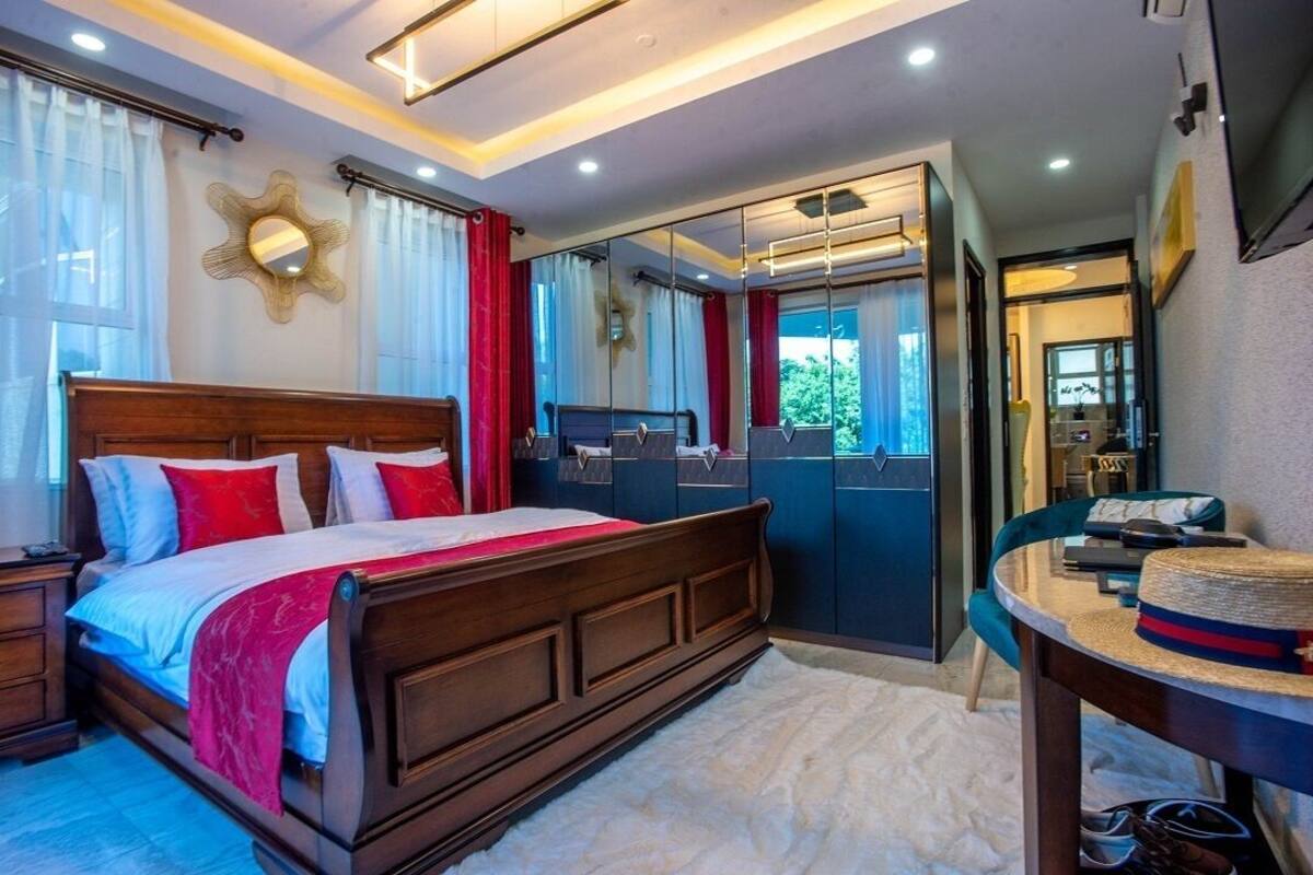 Une chambre à coucher avec un lit en bois, un miroir, une coiffeuse et une vue sur l’extérieur.