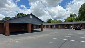 A motel with a covered parking area and a row of rooms. - Sky Inn Hotel (Birmingham)