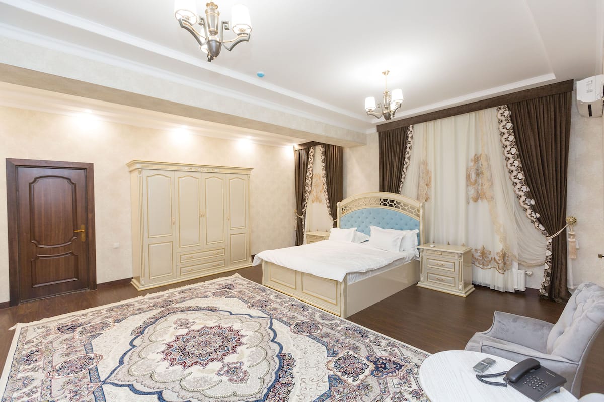 Quarto com uma cama grande, mesa de cabeceira, cadeira, guarda-roupa e um candelabro.