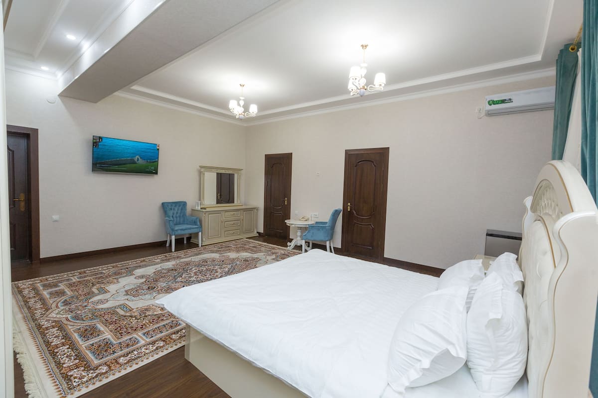 Um quarto com uma cama grande, uma escrivaninha, uma cadeira, uma televisão e um guarda-roupa.