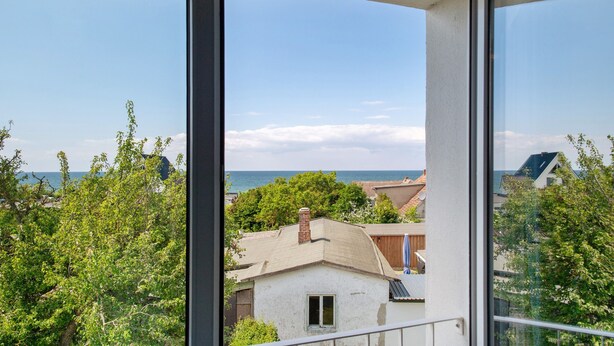 Een balkon met uitzicht op zee en omliggend groen.