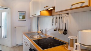 Een moderne keuken met een ingebouwde kookplaat, een koffiezetapparaat en diverse keukengerei aan de muur.