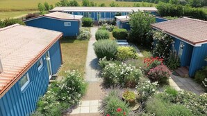 Een rij blauwe stacaravans met een tuinpad ertussen.