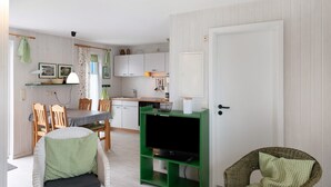 Un espacio habitable compacto con zona de comedor, kitchenette y mueble de entretenimiento verde.