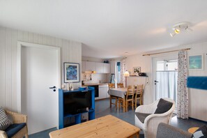 Un espace de vie compact comprenant un coin repas, une kitchenette et un téléviseur placé dans un coin.