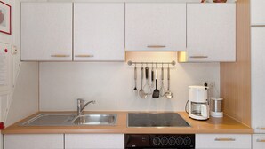 A kitchen with a sink, stove, and coffee maker. - Holiday home "Möve ABA Bungalow 62" with private terrace and WLAN (Rerik)