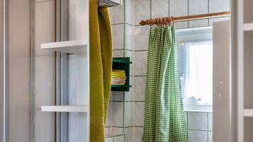 A bathroom with a towel rack, a green towel, and a green checkered bathrobe.