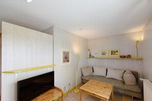 En stue med sofa, træbord, fjernsyn og pejs.