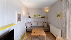 A room with a sofa, a table, a TV, and a radiator. - Holiday home "Möve ABA Bungalow 60" with private terrace and WLAN (Rerik)