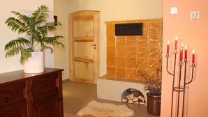 A room with a wooden door, a potted plant, a tiled wall, and a candelabra with candles.