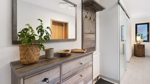 Un tocador de baño con un espejo grande, cajones de madera, una cesta tejida y un cuenco.