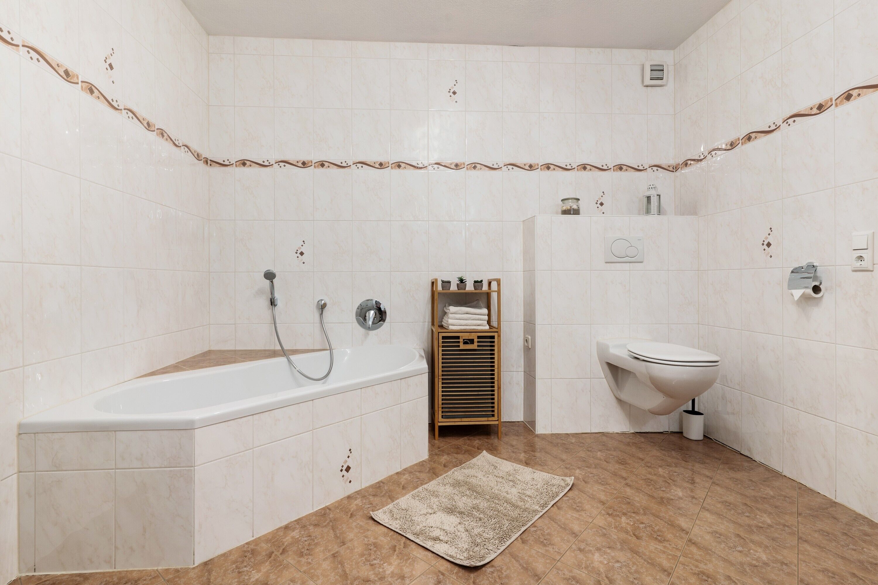 Ein Badezimmer mit Badewanne, Toilette und einem Ablagebereich mit Handtüchern.