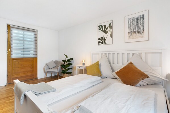 Une chambre à coucher comprenant un lit, une table de chevet, une chaise et une fenêtre avec des stores.