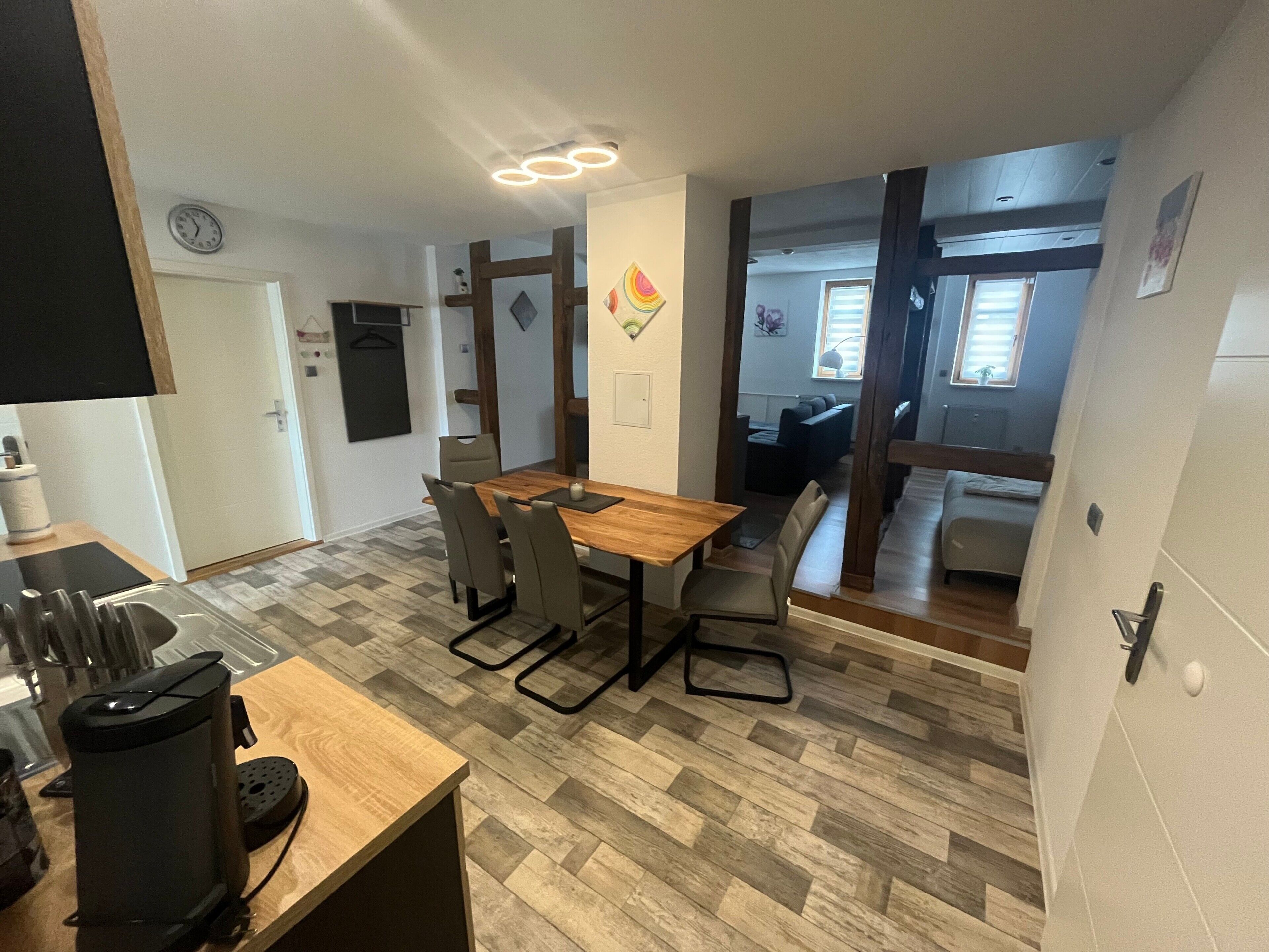 Una cocina moderna con una mesa de madera, sillas y una cafetera.