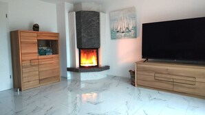 Un soggiorno con camino, televisore e mobili in legno.
