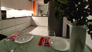 Una cucina moderna con mobili bianchi, un tavolo da pranzo con due bicchieri e piatti, e un vaso con fiori.