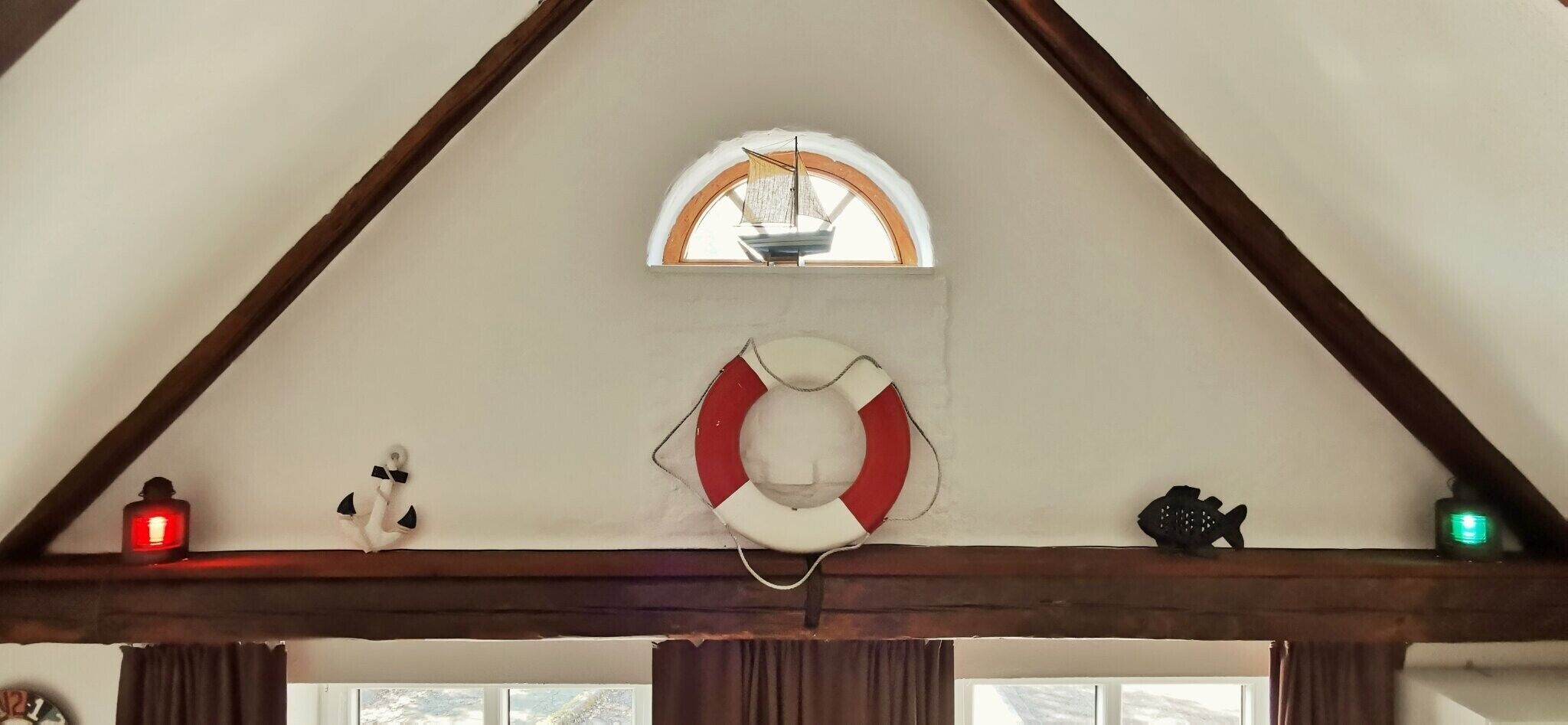 A room with a sloped ceiling, a life preserver decoration, a small anchor, and a fish decoration.