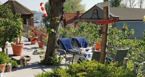 A patio area with outdoor seating, potted plants, and a view of the sea.