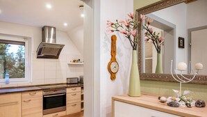 A modern kitchen with a built-in oven, a stainless steel range hood, and a window with a view of greenery. - Apartment 'Haus Heidorn' with Balcony and Wi-Fi (Sittensen)