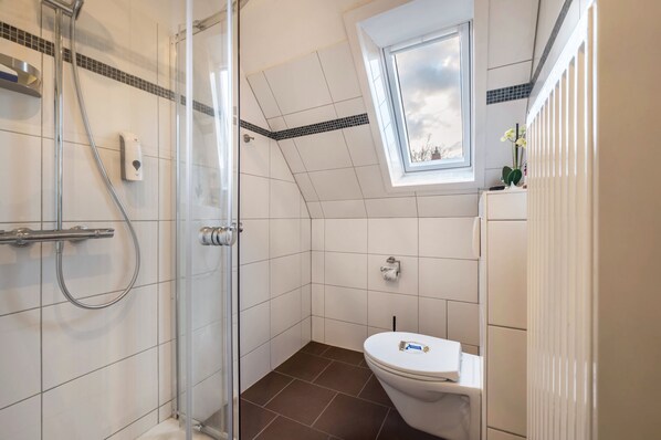 Ein modernes Badezimmer mit Dusche, Toilette und Oberlicht.