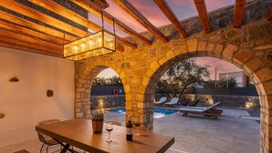 Une terrasse extérieure agrémentée d’une arche en pierre, d’une piscine et de chaises longues.