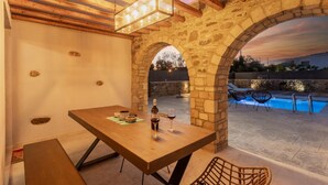 Une terrasse extérieure avec une table en bois, des arches en pierre et une piscine.