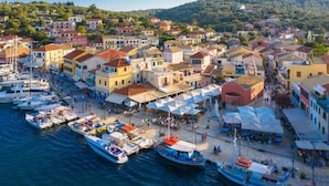 A coastal town with colorful buildings, a marina with boats, and outdoor seating areas. - Villa Gardenia in Paxi (Paxos)