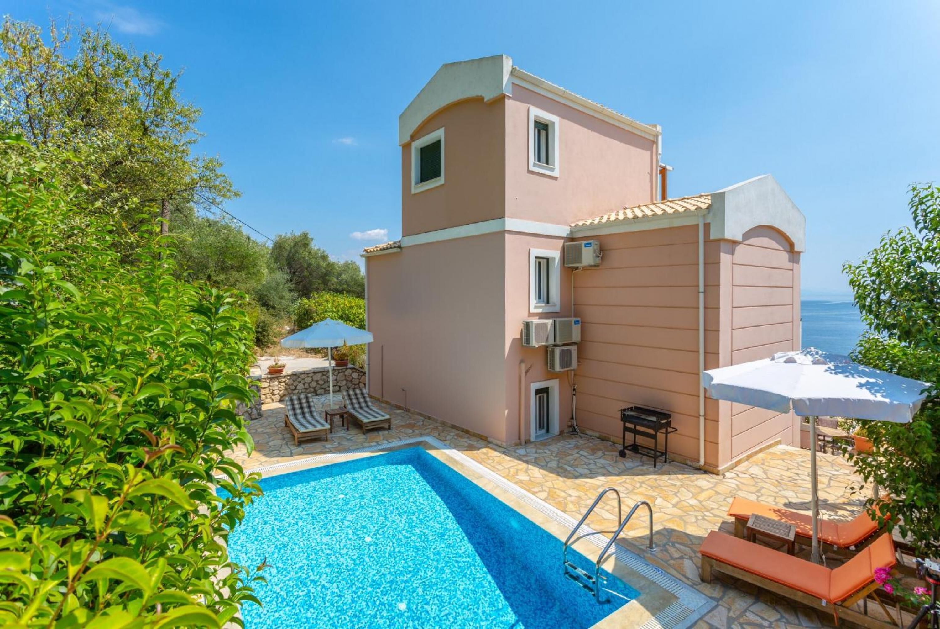 A two-story building with a swimming pool, outdoor seating, and a view of the sea.