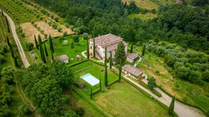 An aerial view of a large estate with a central building surrounded by manicured gardens, a swimming pool, and a variety of trees. - Il Poggio Alle Trese 14 Emma Villas (Citta della Pieve)