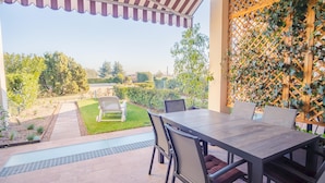 An outdoor patio with a dining table and chairs, a small garden area, and a wooden lattice structure. - Residenza Del Porto - Italian Homing (Padenghe sul Garda)