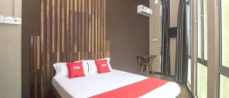 A hotel room with a bed, a wooden slat wall, an air conditioning unit, and a window with curtains.
