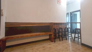 Eine Holzbank und zwei Hocker in einem Raum mit Holzboden und weißen Wänden.
