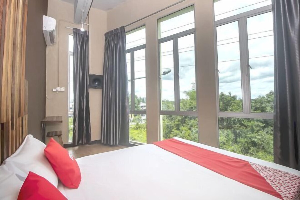 A hotel room with a large bed, a TV, and a view of the outdoors.