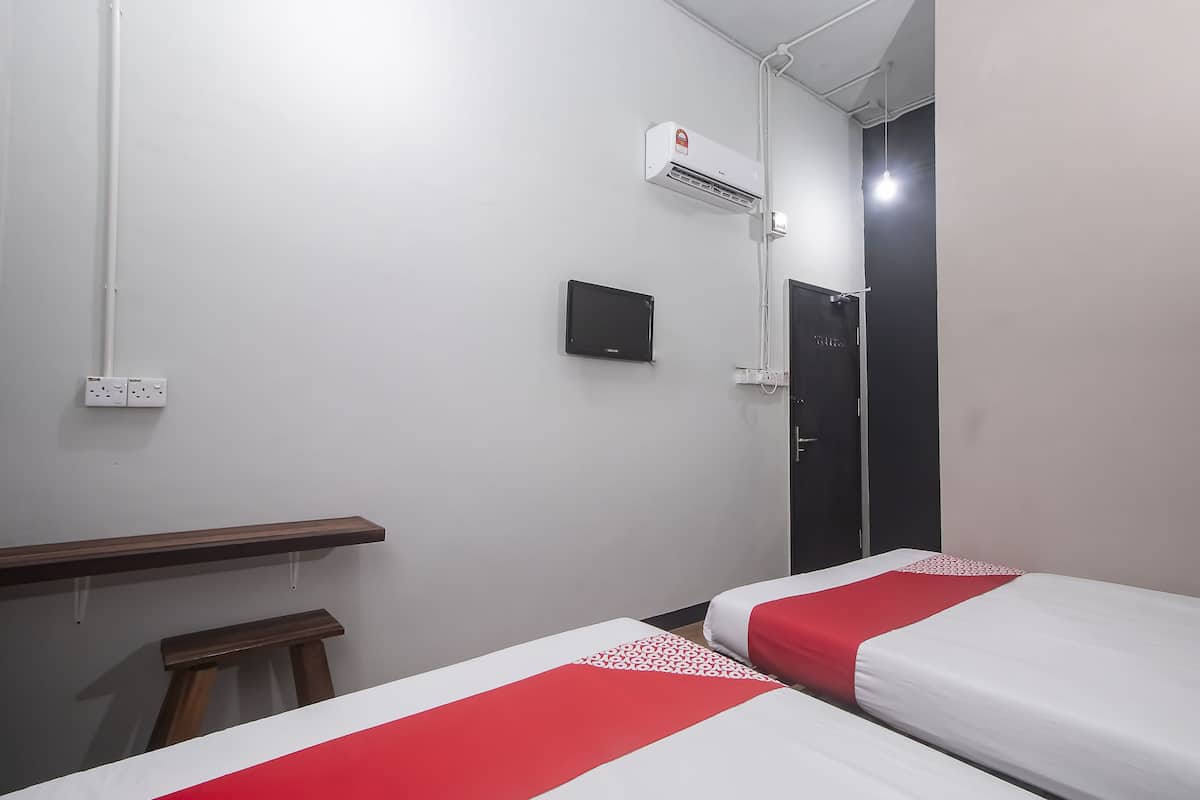 A hotel room with two beds, a desk, a chair, an air conditioning unit, and a door.