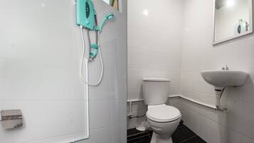Un baño con inodoro blanco, lavamanos y cabina de ducha.