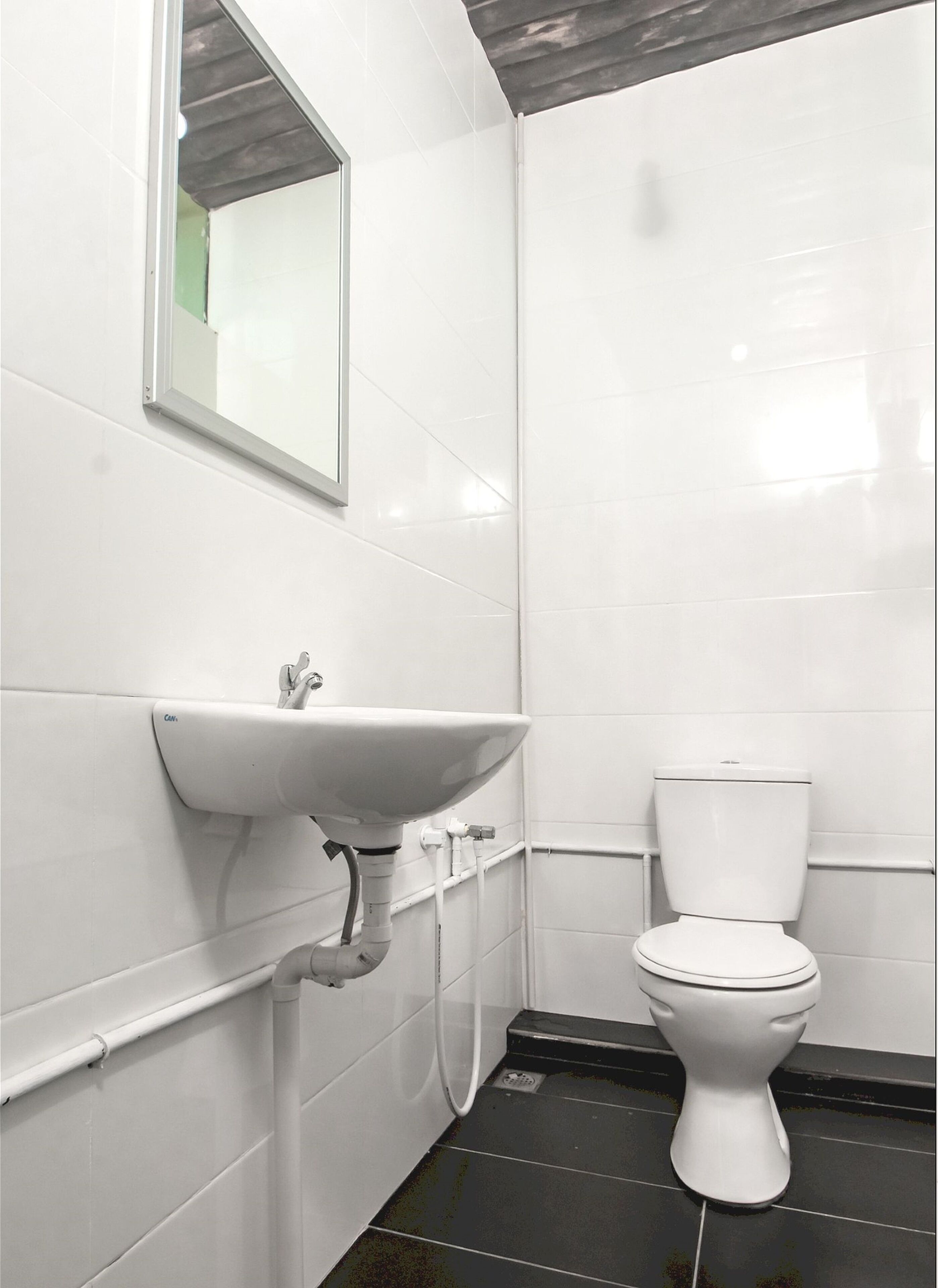 Een compacte, moderne badkamer met een wit wastafelmeubel, toilet en een spiegel aan de muur.