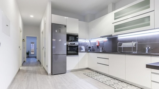 A modern kitchen with stainless steel appliances, white cabinetry, and a black countertop.