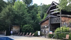 Eine Holzhütte mit Pool und Liegestühlen.