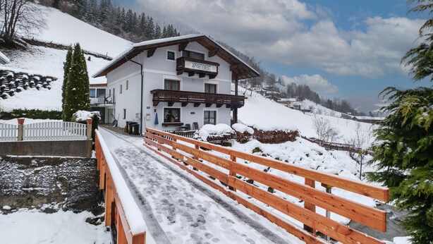 Un immeuble de deux étages avec une enseigne indiquant « APPartement » et une terrasse en bois menant à l’entrée.