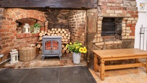 A rustic stone fireplace with a wooden bench and a table nearby. - The Brewhouse (Church Stretton)