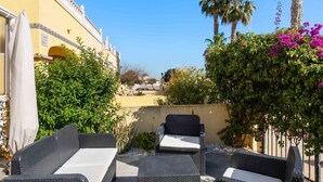 Eine Terrasse im Freien mit Korbmöbeln und Blick auf ein Gebäude mit der Aufschrift 'Casa Eric'.
