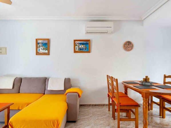 Une pièce comprenant un canapé-lit, une table à manger avec des chaises et deux tableaux encadrés accrochés au mur.