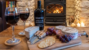 A wooden table with a bottle of port wine, two glasses of red wine, cheese, grapes, crackers, and a cheese knife. - Moorhens - Cotswold Water Park (Cotswold Water Park)