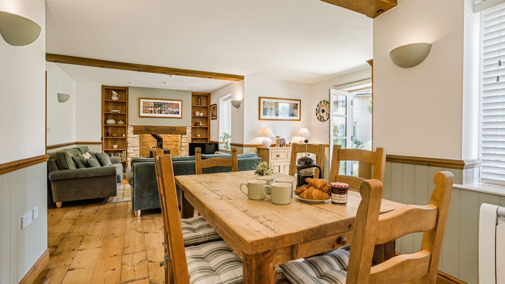 Een gezellige woonkamer met een open haard, een eettafel met stoelen en een bank.