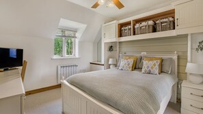 Une chambre à coucher comprenant un lit, une télévision, une fenêtre et des rangements intégrés.