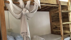 Un letto a castello con materasso bianco, struttura in legno e testiera con tende legate a un fiocco.